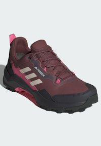 Burgunderrote Wanderschuhe mit atmungsaktivem Mesh-Obermaterial, pinken Akzenten und grauen Streifen. Sie verfügen über eine gepolsterte Sohle mit robustem Profil für hervorragenden Halt.