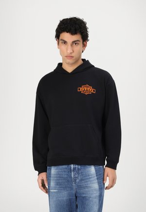 Sort hoodie lavet af bomuld, med en central kengurulomme og et orange "DIESEL" logo. Bæres med lyseblå jeans.