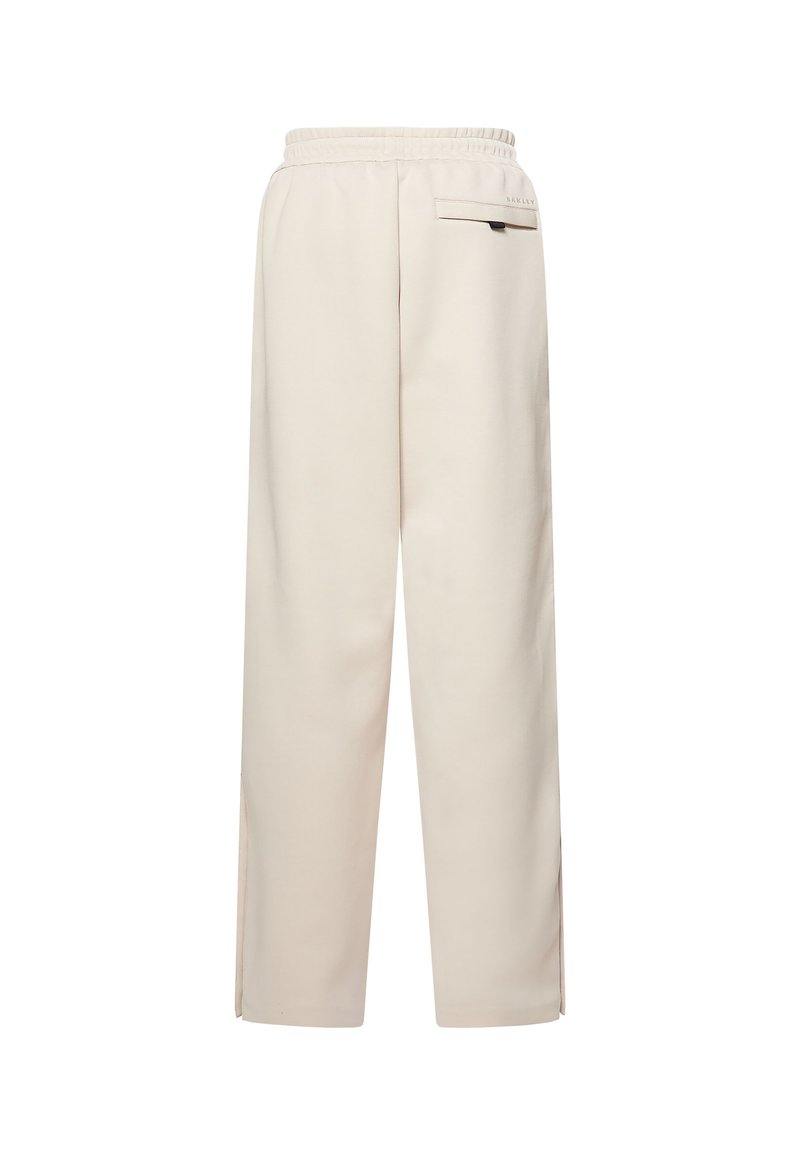 Pantalones beige de pierna ancha con cintura elástica, bolsillo trasero con solapa y pequeñas aberturas laterales en el dobladillo.