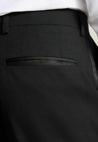 Schwarze formelle Hosen mit glatter Textur, ausgestattet mit einer kleinen versteckten Tasche mit Satinbesatz und einer taillierten Passform an der Taille.
