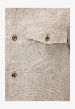 Camicia in tessuto a quadri beige con due bottoni in legno sul davanti e una tasca con patta e bottone sul petto.
