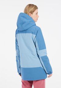 Blauwe skijack met een capuchon, met een color-block ontwerp in verschillende blauwtinten, elastische manchetten en een rechte snit.