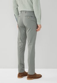 Grijze op maat gemaakte broeken met achterzakken en een zichtbare knoopdetail. Draag ze met een lichtgroen shirt en bruine suède schoenen.