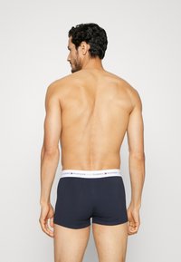 Dunkelblaue Boxershorts mit einem weißen Bund, der das Logo "TOMMY HILFIGER" trägt. Glatte Textur, enganliegendes Design, mittlere Oberschenkellänge.
