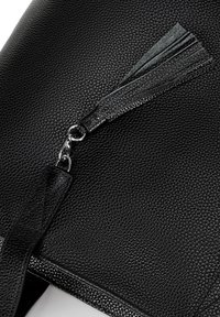 Borsa a mano in pelle nera con finitura testurizzata, dotata di un inserto in metallo argentato a forma di tassello per la zip e un accento in pelle liscia.