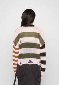 Gestreepte gebreide trui met horizontale strepen in roze, groen, bruin en zwart; met rafelige randen en een losse pasvorm.