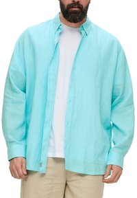 Lichtblauw overhemd met lange mouwen, gemaakt van een gestructureerde, lichte stof met knoopsluiting en een ontspannen pasvorm. Draagt over een wit T-shirt.