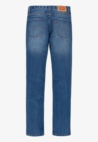 Vaqueros de denim azul con corte recto, que presentan una etiqueta de cuero en la cinturilla, dos bolsillos traseros y costuras en contraste.