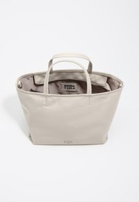 Beżowa torba na ramię z podwójnymi uchwytami, gładką skórzaną fakturą, otwartym wierzchem i wewnętrzną metką. Minimalistyczny design o kwadratowym kształcie.