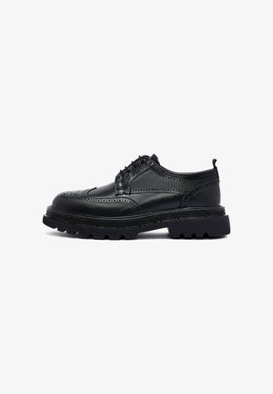 Chaussures brogue en cuir noir avec des perforations décoratives, dotées d'une semelle en caoutchouc noir épaisse et d'un design à lacets. Fini lisse et poli.