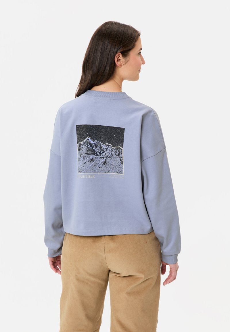 Hellblaues Sweatshirt mit cropped Design, auf der Rückseite mit einem Schwarz-Weiß-Bergmotiv und gerippten Bündchen.