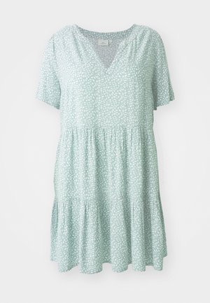 Lys grøn kjole med v-udskæring, korte ærmer og en samlet lagdelt nederdel. Har et hvidt bladmønster over det hele.