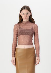 Hnědý dlouhý rukávový crop top z průhledné látky s opakovaným logem "HUGO". V kombinaci s hnědou koženou sukní s vysokým pasem.