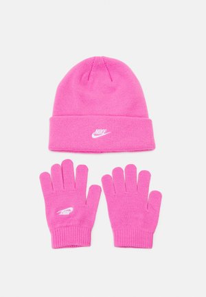 Bonnet en tricot rose avec revers et logo Nike blanc ; gants en tricot rose assortis avec doigts ouverts et logo Nike blanc sur le poignet.
