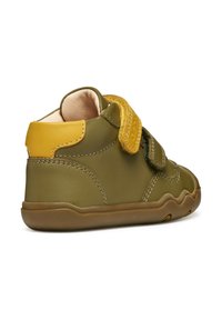 Scarpa in pelle verde oliva con retro giallo, cinturino in velcro e suola in gomma. Presenta dettagli cuciti e bordi arrotondati.