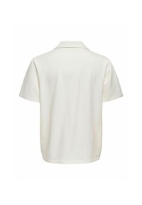 Polo à manches courtes texturé couleur blanc cassé avec un col à pointe, vu de dos sur un fond blanc uni.