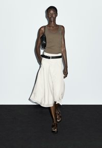 Bruine tanktop, witte A-lijn rok met een zwarte riem en bruine sandalen. Zwarte handtas op de schouder, gladde textuur, minimalistisch ontwerp.