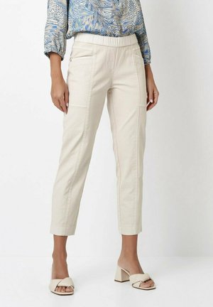 Light beige cropped pants with a smooth texture, featuring a soft elastic waistband and front pockets. Paired with a blue patterned top.