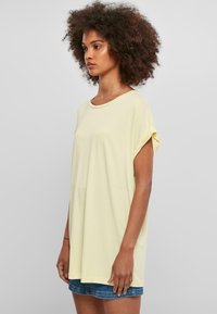 Lys gul, kortærmet T-shirt lavet af blødt bomuld. Løs pasform med rund halsudskæring og opkrøllede ærmer.