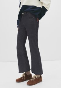 Jeans din denim închis cu tiv brut, buzunare frontale �și cusături deschise. Purtați cu adidași din suede maron și sosete crem.