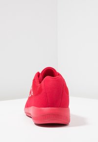 Rode sportieve schoen met een gladde stoffen bovenzijde en meshdetails. Dikke rode zool met profielpatroon. Witte logo op het zijpaneel.