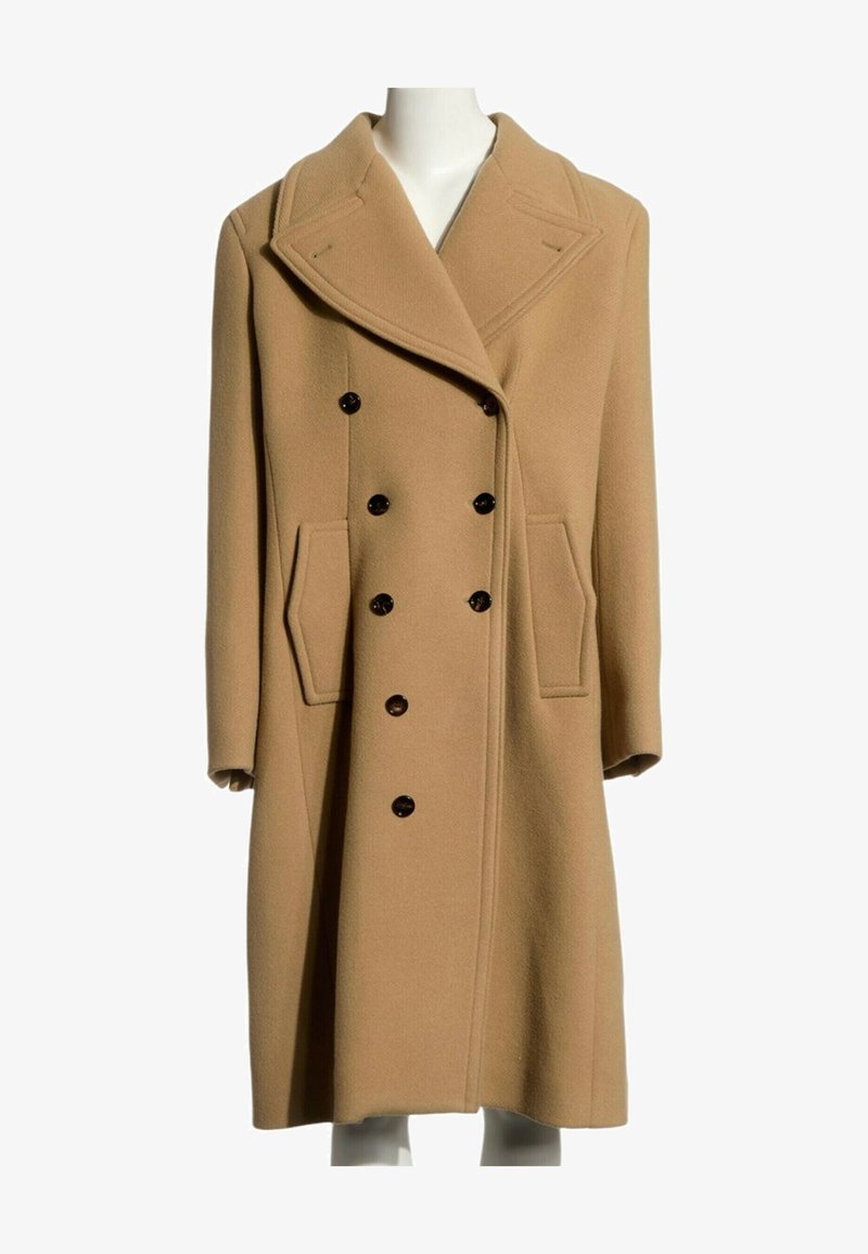 Manteau en laine couleur camel, à double boutonnage, avec larges revers, poches latérales et boutons noirs, présenté sur un mannequin blanc.