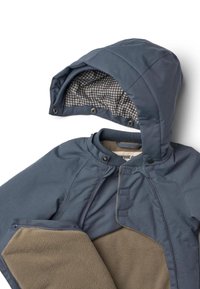 Sininen ulkotakki, jossa on harmaa fleecvuori, tikattu huppu, painonappikiinnitykset ja vetoketjut sekä vaaleanbeiget fleeceyksityiskohdat edessä.