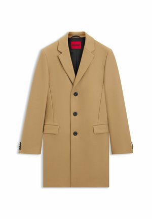 Beige kavaj med slag, tre svarta knappar, sidofickor och svart inredning. Slät textur med en strukturerad design.