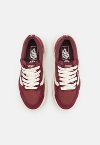 Par tenisica marke Vans boje burgundac s bijelim vezicama i kremastim đonovima, prikazanih odozgo na bijeloj pozadini.