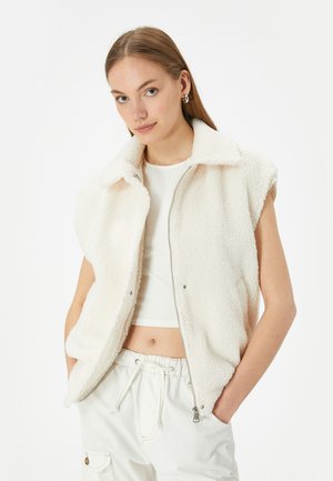 Fleece vest i off-white med lynlås foran, krave og ærmeløs design. Blød tekstur, med to sidelommer.