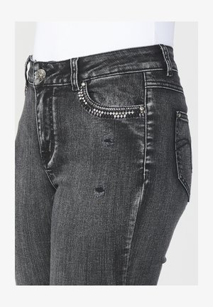 Zwarte denim jeans met een slanke pasvorm, voorzien van versleten details en decoratieve gespikkelde accenten op de voorkeurszak. Heeft ook een standaard knoopsluiting.