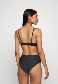 Black bikini set featuring adjustable straps, a hook closure at the back, and high-waisted bottoms. Smooth fabric with minimal detailing.
