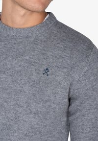 Suéter gris de punto con cuello redondo, que presenta un pequeño logotipo bordado en navy en el lado izquierdo del pecho y puños acanalados.