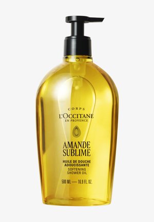 Flaske med L'Occitane Amande Sublime blødgørende shower olie med sort pumpe, kapacitet 500 ml, gyldengul gennemsigtig beholder.