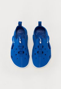 Blaue Gummislipper mit Ausschnitten, strukturiertem Obermaterial und weißen Akzenten. Verfügt über eine Zuglasche und einen zentralen Riemen für einen sicheren Sitz.