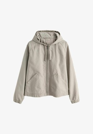Jachetă bej deschis cu glugă și fermoar, cu buzunare frontale și manșete elastice, realizată dintr-un material moale și casual.