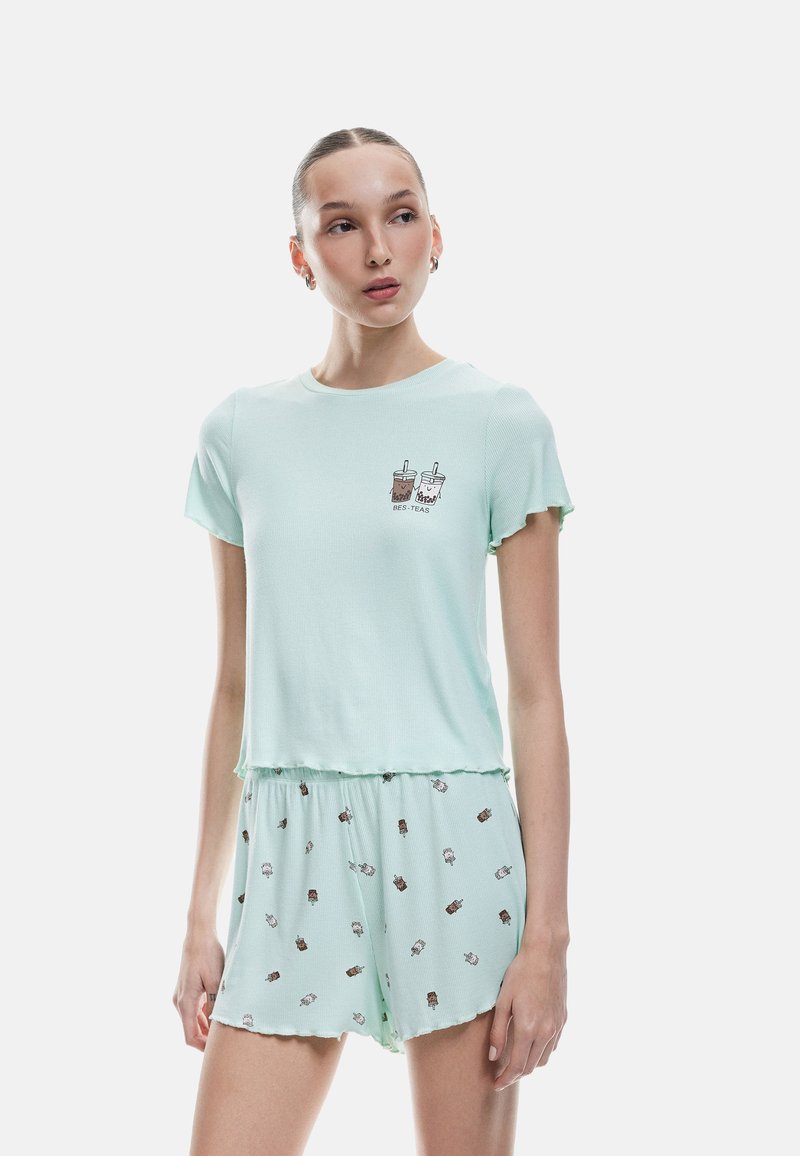 Mintgrünes Pyjama-Set mit Kurzarmoberteil, das eine Getränke-Grafik zeigt, und passenden Shorts mit einem durchgehenden Eiscreme-Muster.