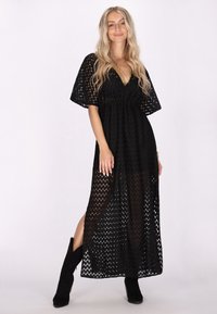 Abito maxi nero fluido con scollatura a V, maniche corte e un motivo testurizzato, caratterizzato da spacchi laterali e una vita accentuata.