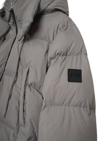 Chaqueta acolchada gris con capucha, con cremallera frontal, un bolsillo exterior y un parche de logo negro en la manga. Textura de tejido suave y brillante.