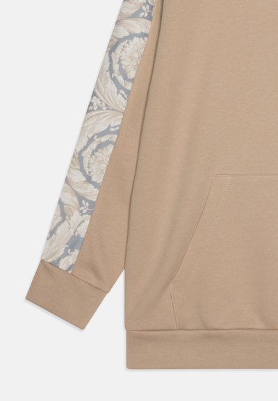 Bež kapuutsärg, millel on tekstuuriga kangas, pikal varrukal on heledates toonides lillemuster sinisel taustal. Kaasas on kängurupocket.