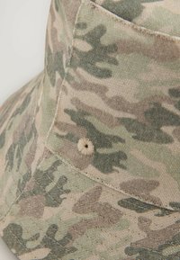 Camouflage emmerhoed gemaakt van zachte stof, met een ronde kroon, een zwerende rand en een kleine gestikte accent aan de zijkant.