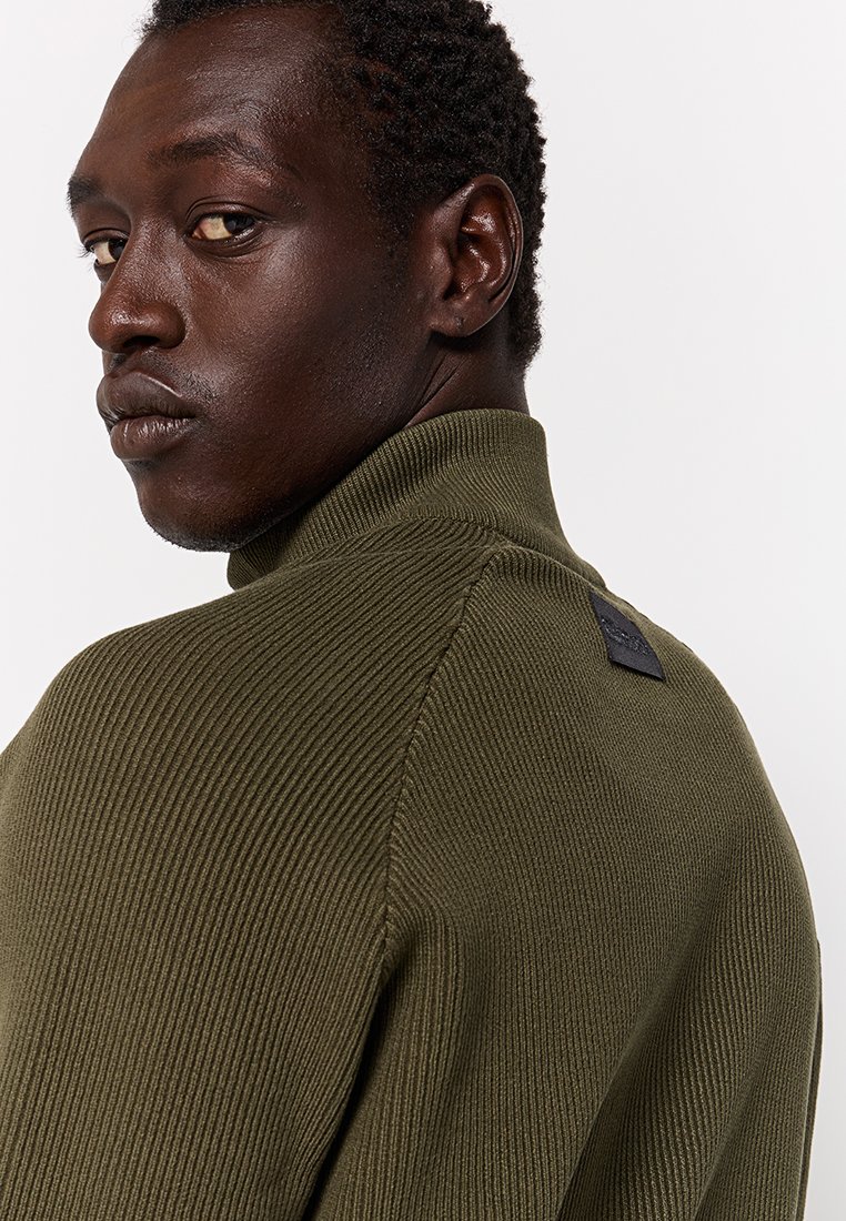 Maglione a coste verde oliva con alto colletto e tessuto testurizzato; presenta una piccola etichetta nera sul retro vicino al colletto.