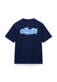 Μπλε μπλουζάκι από βαμβάκι σε ναυτικό μπλε χρώμα με μεγάλο λογότυπο σε ανοιχτό μπλε γραφικό στυλ, που γράφει "Napapijri" και "Since 1987" στην πλάτη. Με κοντά μανίκια και στρογγυλή λαιμόκοψη.