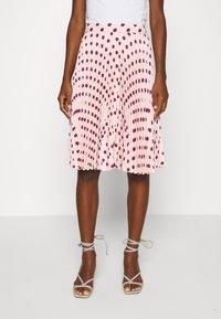 Pitskirt i ljusrosa tyg med vinröda prickar. Har en midilängd och elastisk midja för komfort.