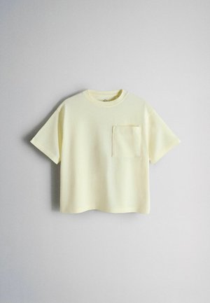 T-shirt z krótkim rękawem, w jasnożółtym kolorze, wykonany z bawełny, z kwadratową kieszenią na lewej piersi. Swobodny krój i okrągły dekolt. Gładka faktura.
