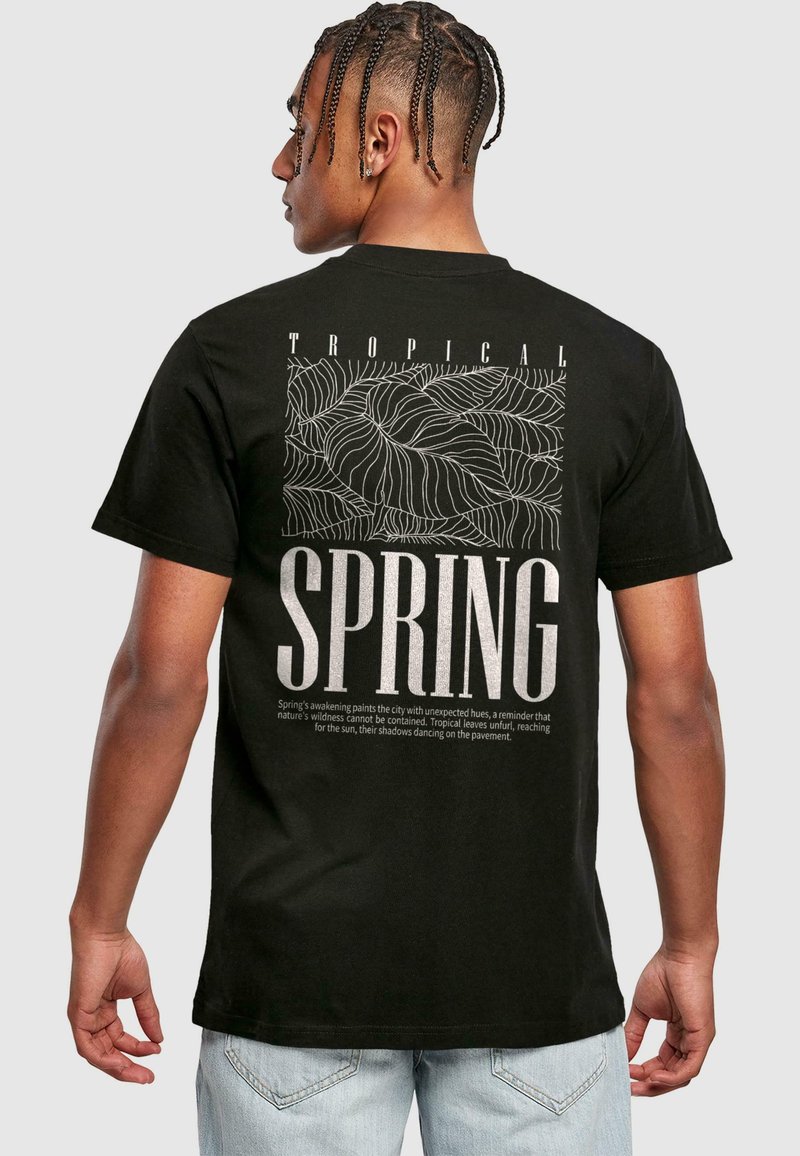 Sort bomulds T-shirt med et tropisk bladdesign og fed tekst i hvid "FORÅR", samt en detaljeret tekst, der beskriver årstidens essens.