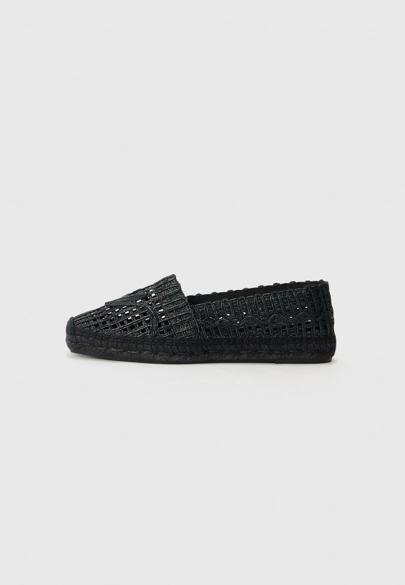 Black woven slip-on shoe with a textured upper and braided jute sole. Features a round toe and decorative stitching accents.