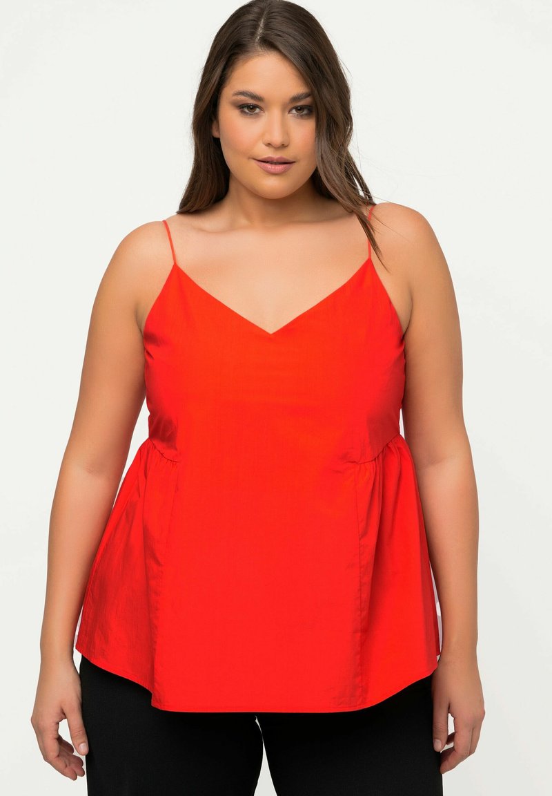 Top rosso con scollo a V, senza maniche, dotato di sottili bretelle a spaghetto e un orlo delicatamente svasato. Texture liscia, realizzato in tessuto leggero.