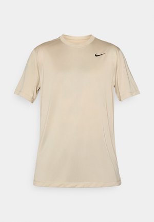 Beige kortærmet Nike sportstrøje med rund hals og lille sort Nike swoosh-logo på forsiden af højre bryst.