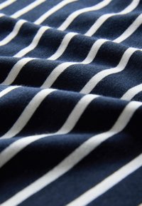 Tissu bleu marine doux avec des rayures blanches horizontales uniformément espacées et des plis de texture visibles.